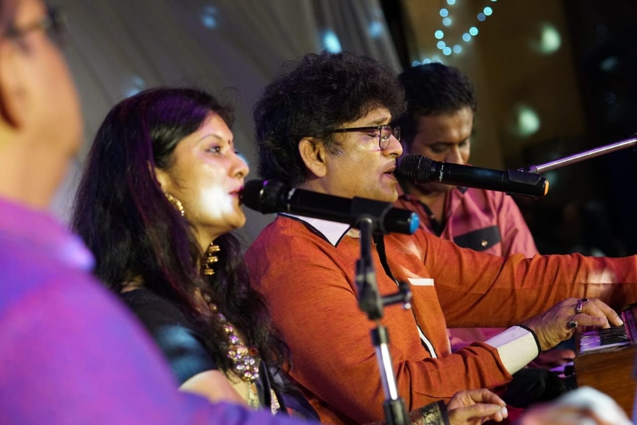 Sanjay Banubakode and Sanjyot singing side by side, warm stage light