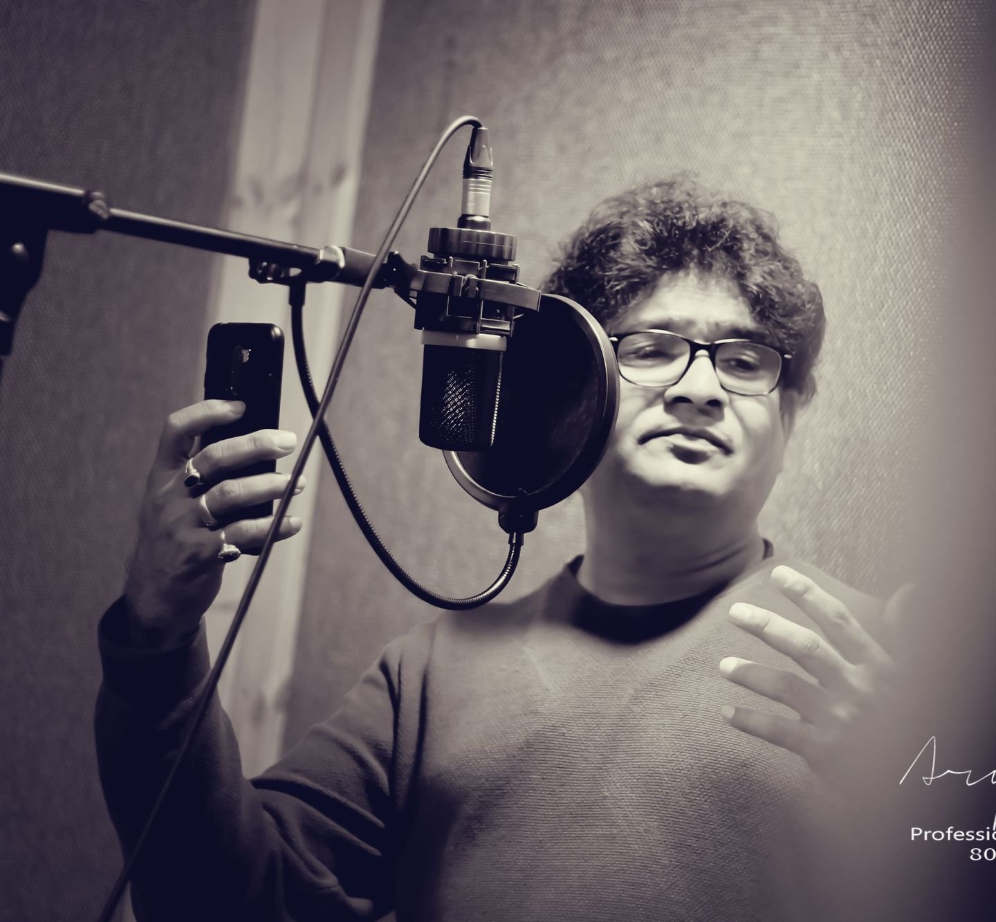 Black-and-white photograph of Sanjay Banubakode at a studio microphone