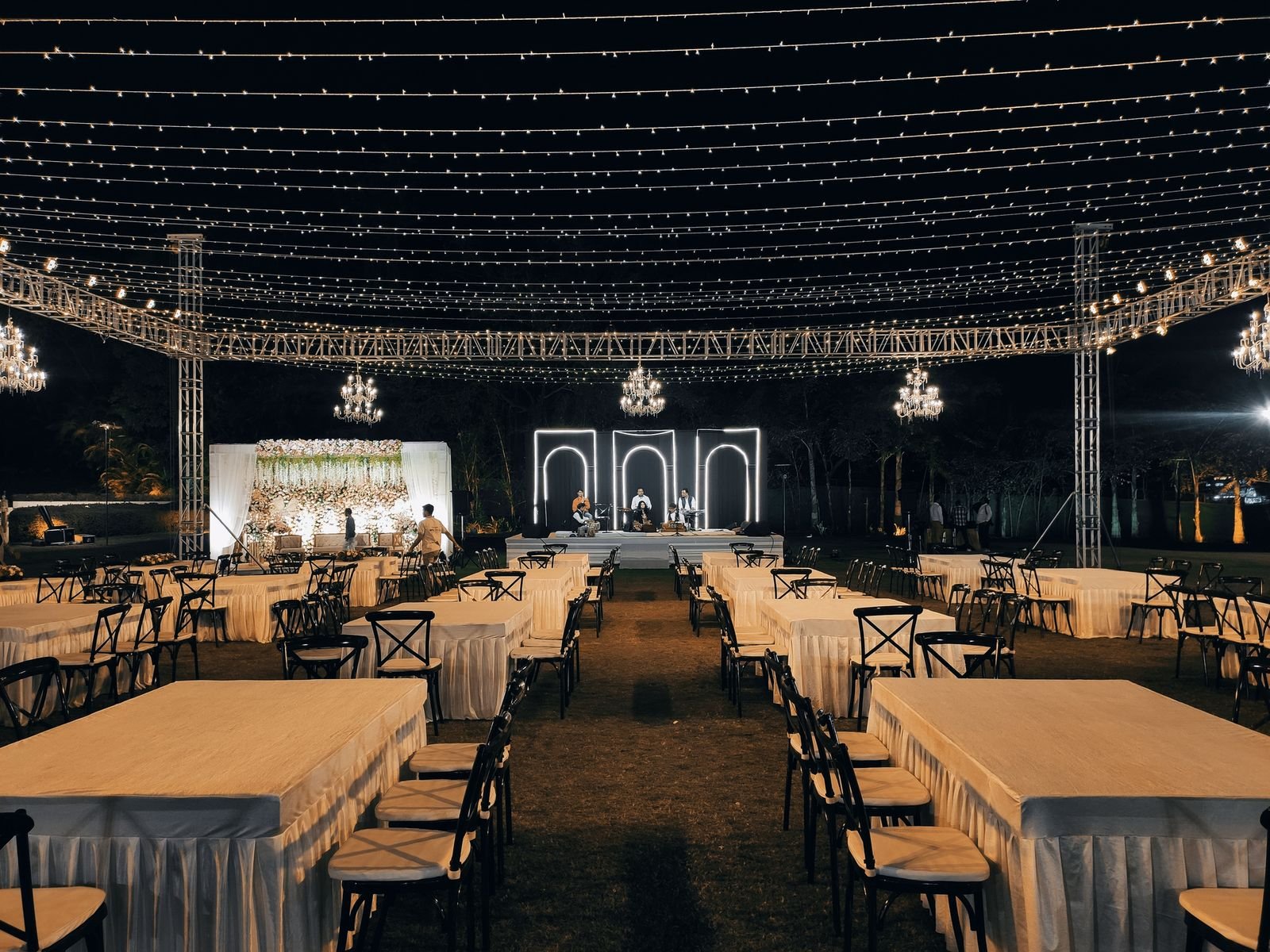 The same arches stage seen from the back of the lawn, string lights overhead