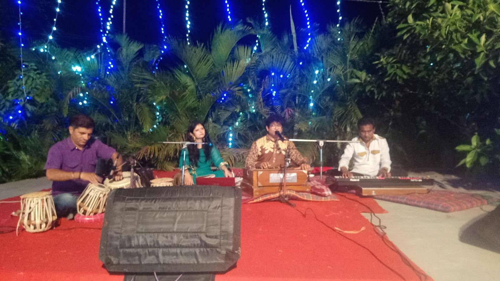 Outdoor mehfil under blue string lights with tabla and harmonium