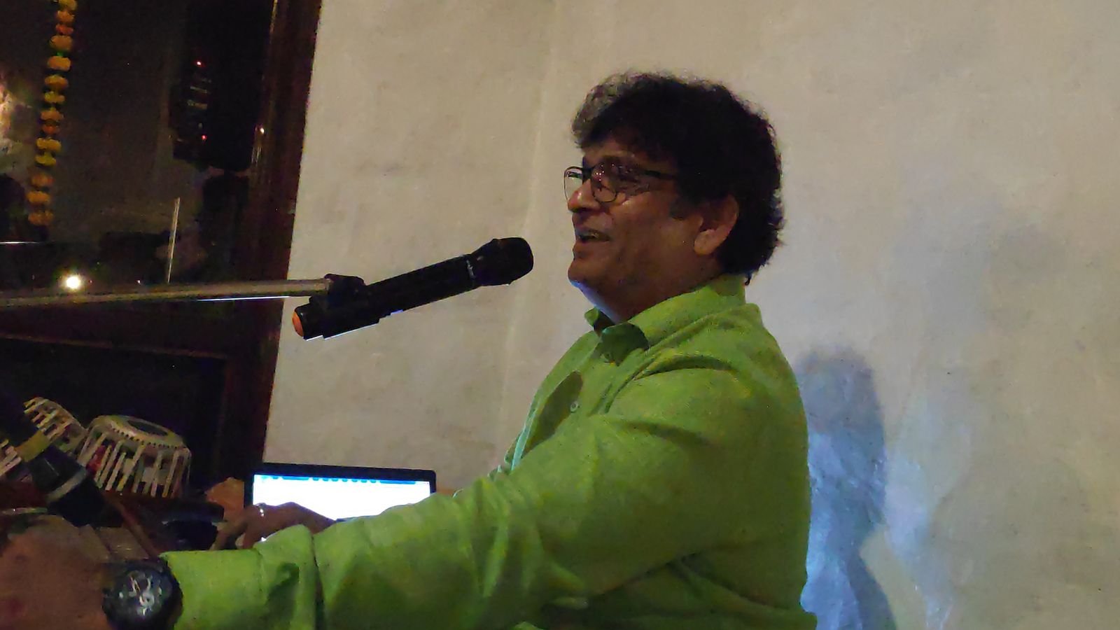 Sanjay Banubakode singing, green shirt, harmonium in front