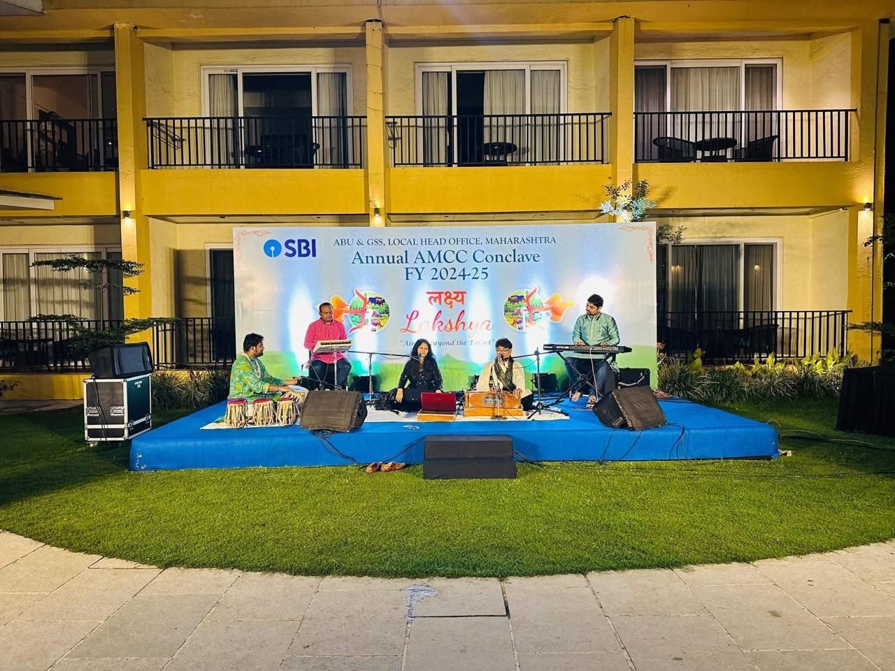 Night lawn stage with lanterns and a tree overhead