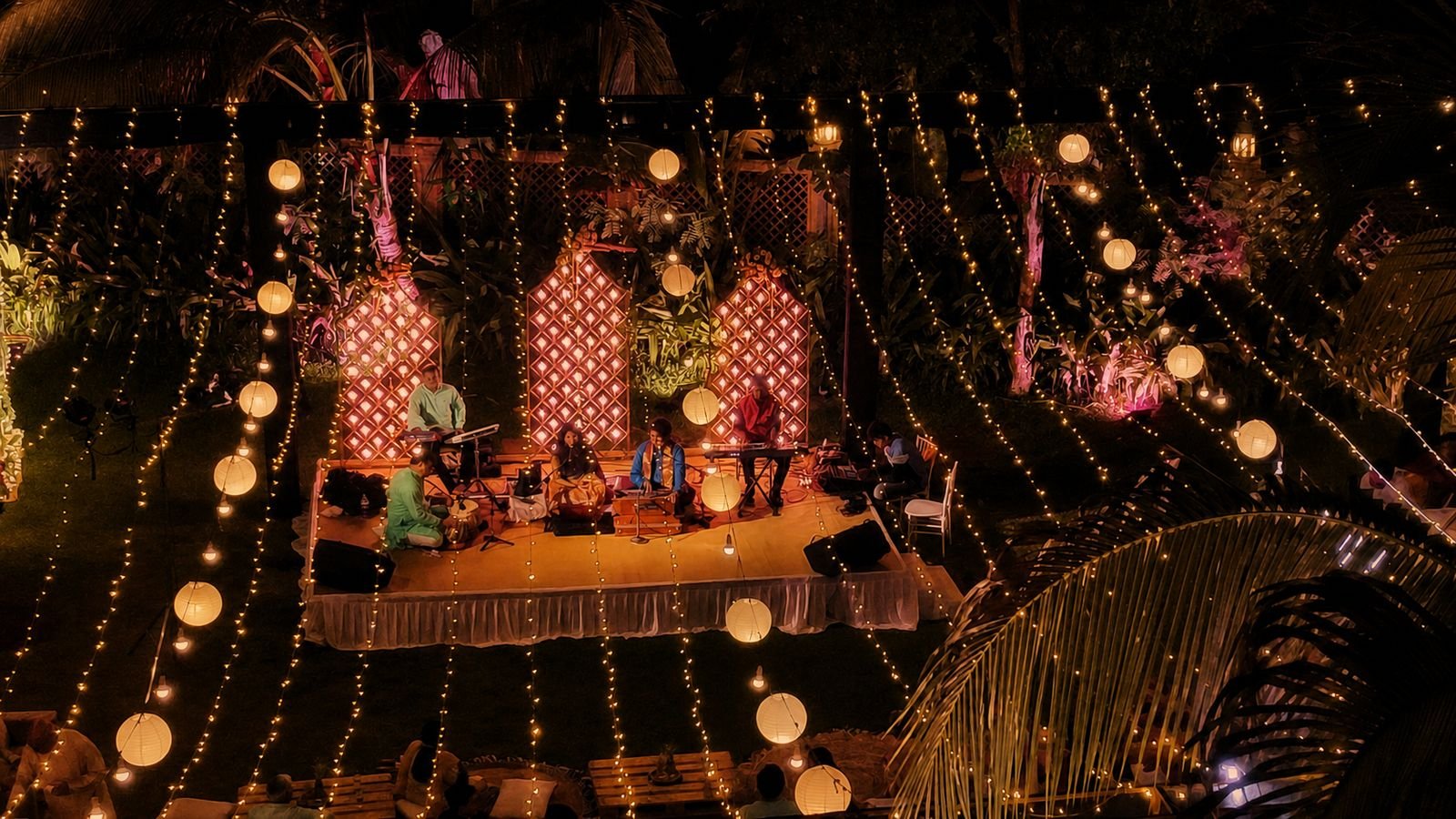 Wide view of an outdoor stage with lattice arches and hanging lights