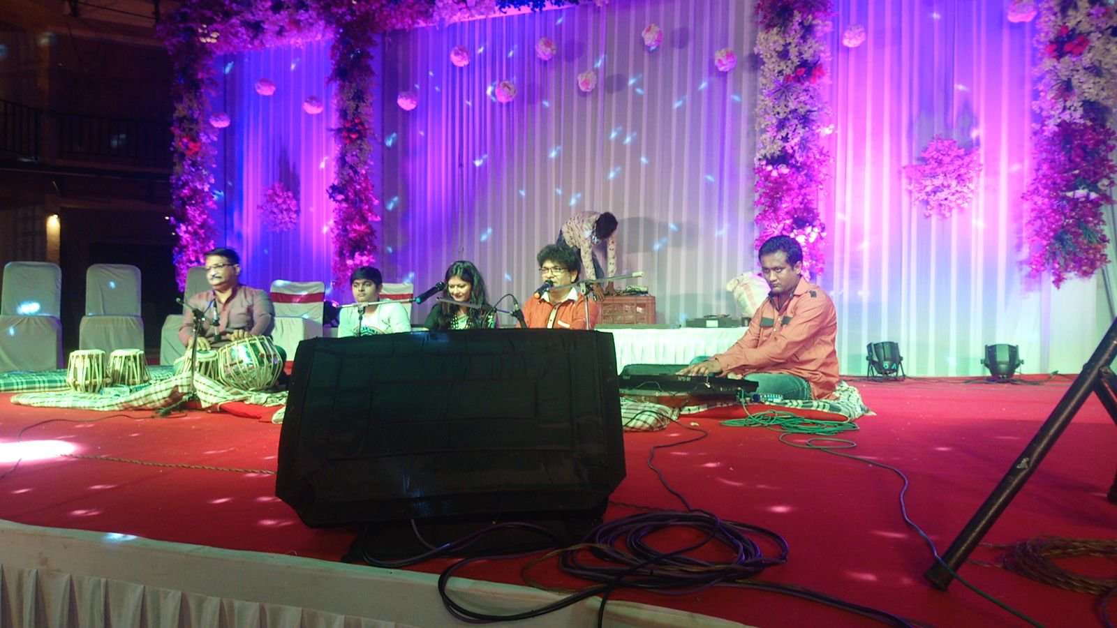 Ensemble on a floral-decorated stage lit in pink and purple