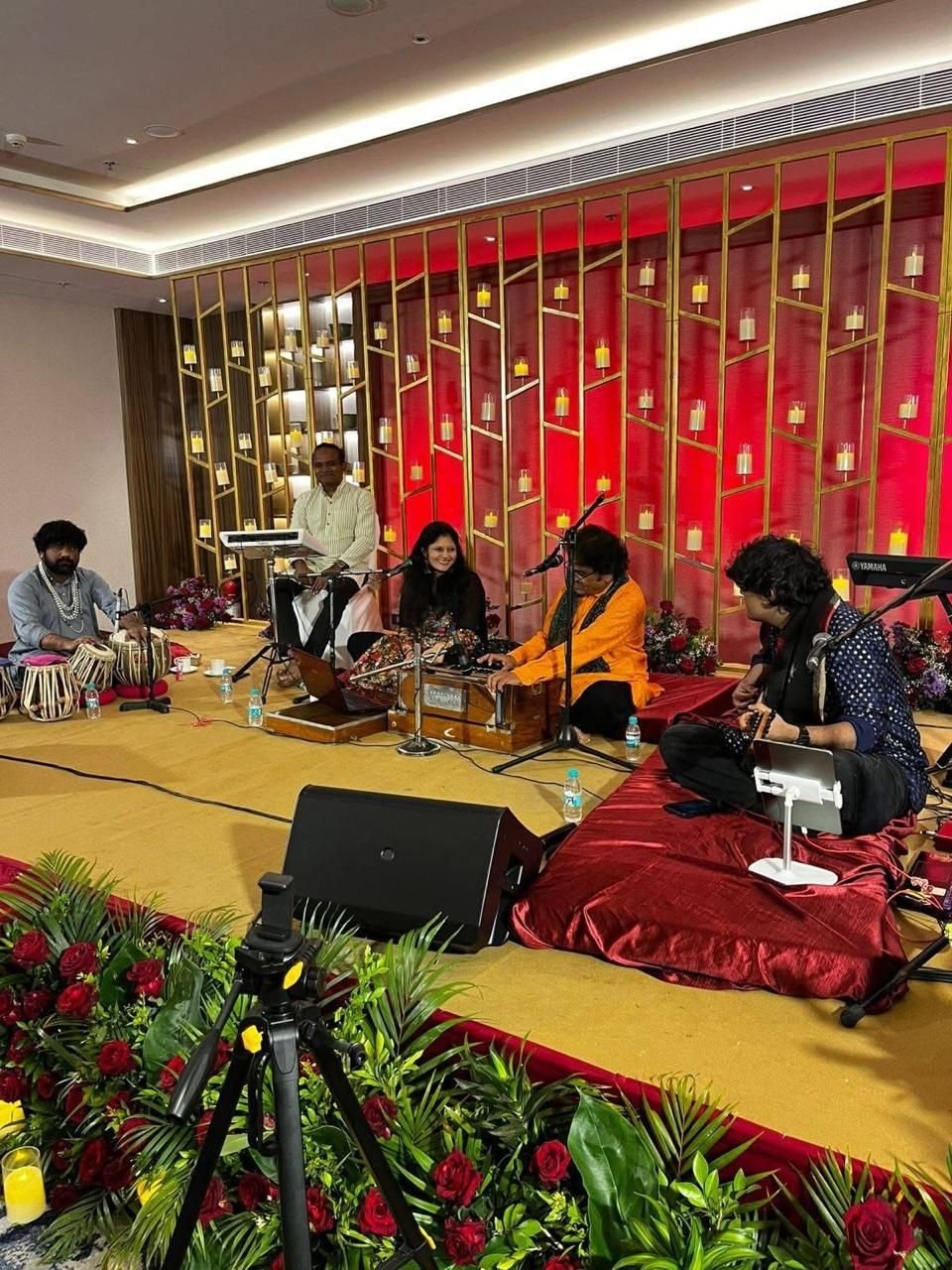 Hotel ballroom mehfil with a red lattice wall and roses
